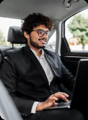 Man working on a laptop in the back seat of a taxi